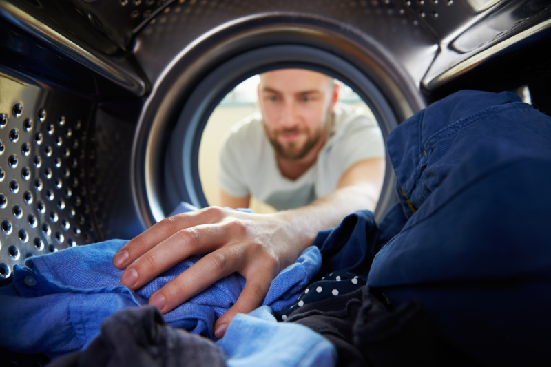 Homme récupérant des vêtements dans un sèche linge